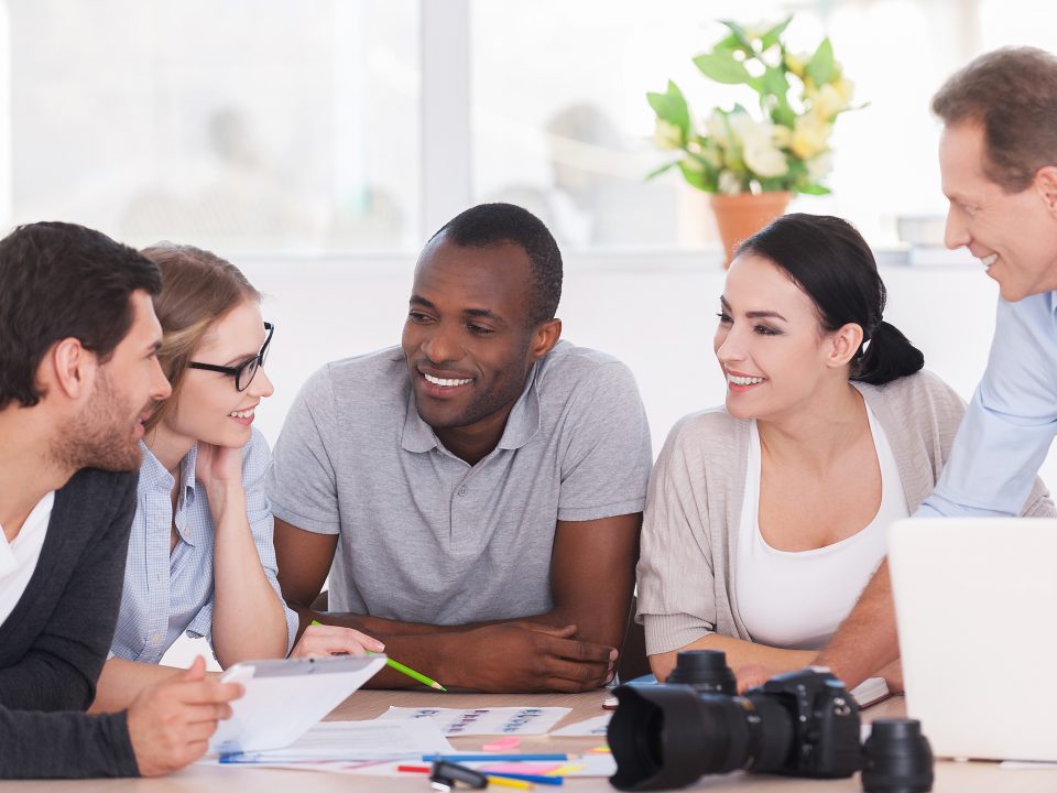 equipe de marketing em uma reunião conversando e sorrindo, trabalhando com alegria e entusiasmo.