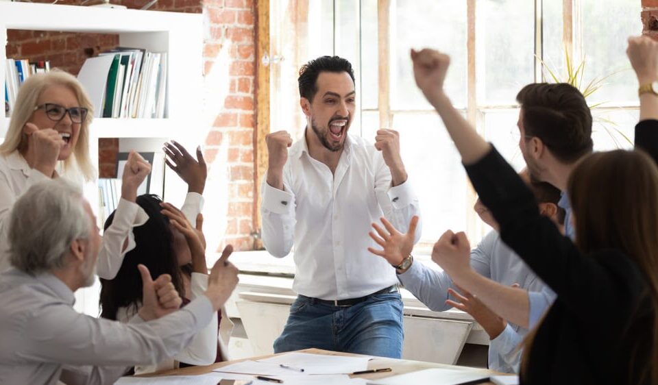 Equipe vibrando os resultados atingidos e comemorando vitórias no ambiente de trabalho