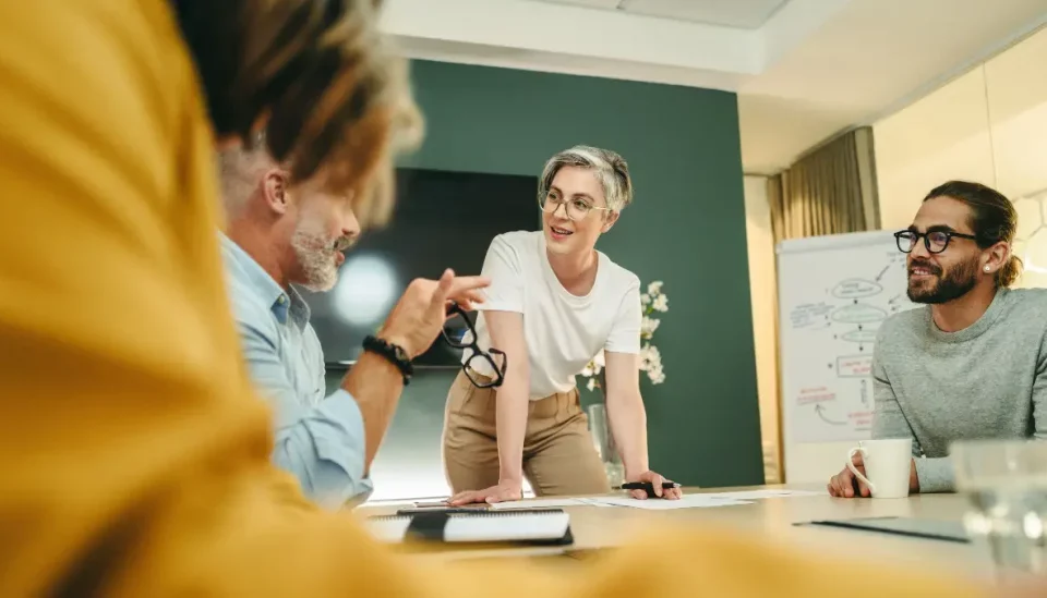 Líder mentor(a) e equipe de marketing discutindo estratégias para campanha de um novo produto