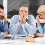 Equipe em reunião com clima tenso, representando a toxidade nas organizações e a importância de ambientes de trabalho saudáveis.