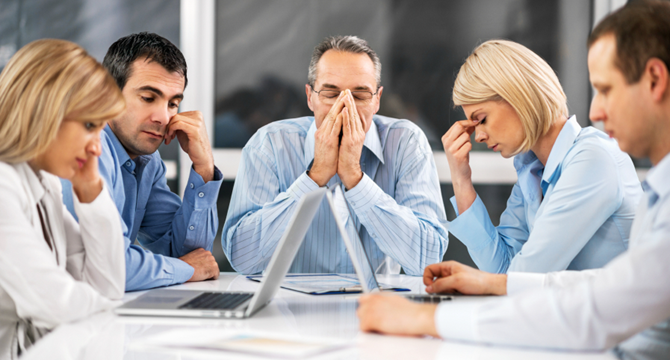 Equipe em reunião com clima tenso, representando a toxidade nas organizações e a importância de ambientes de trabalho saudáveis.